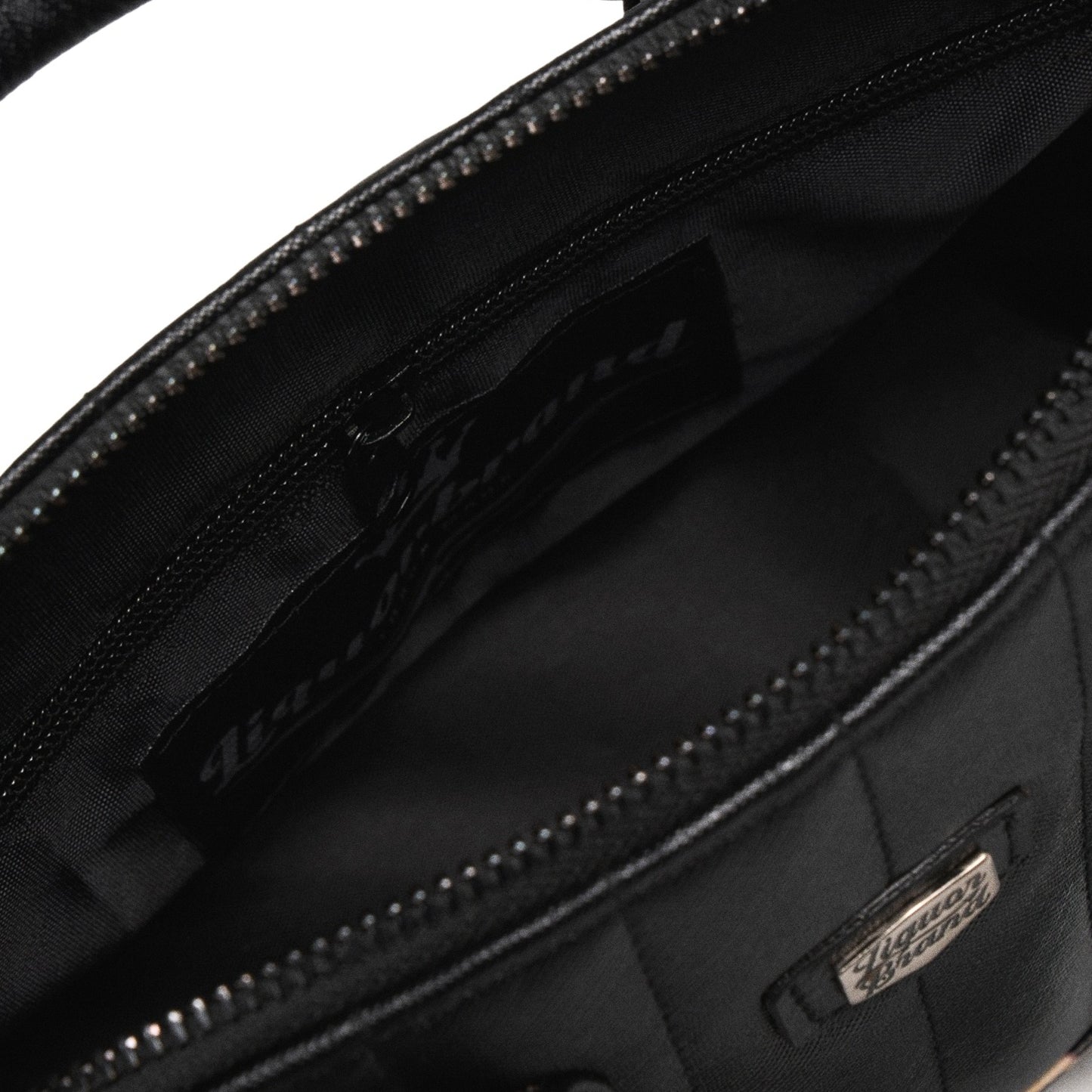 Interior del bolso Lil' Rocket con el forro negro y el bolsillo lateral con cremallera.