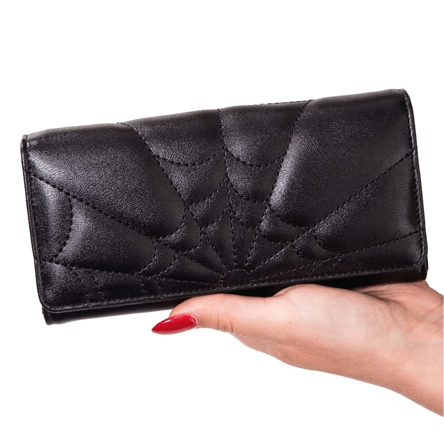 Cartera gótica con diseño de telaraña sostenida en una mano para mostrar su tamaño.