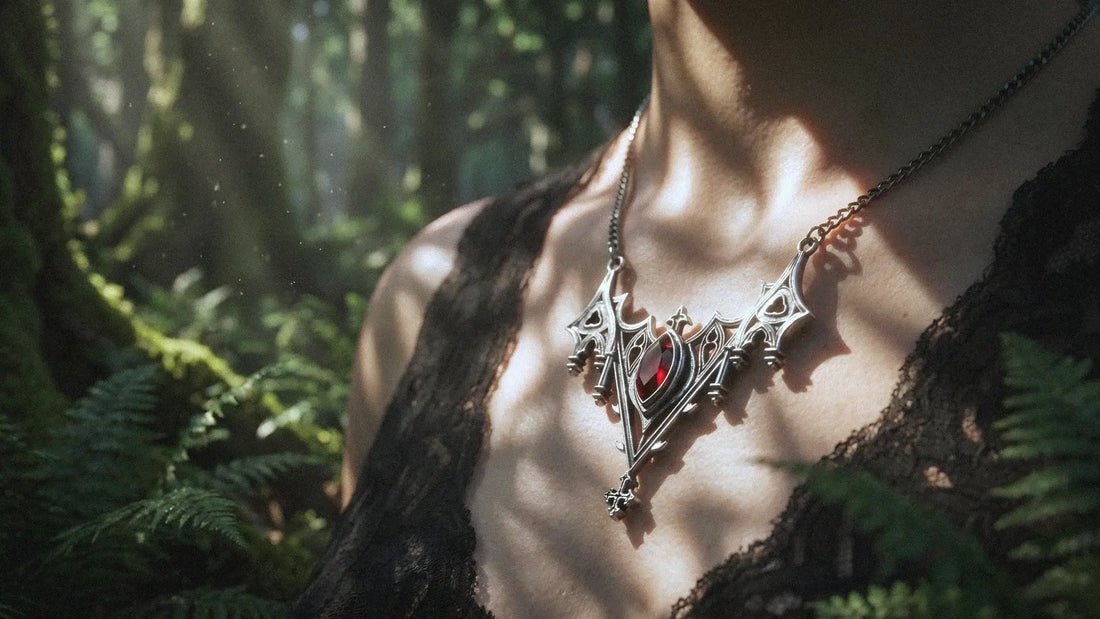 Close-up of a gothic silver cross pendant necklace with a red gemstone, worn over a black lace top, illuminated by dappled sunlight in a lush green forest