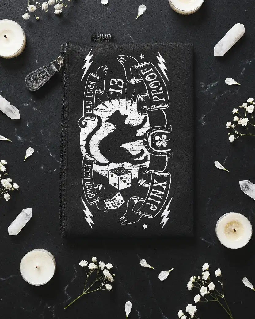 neceser jinx proof de liquorbrand apoyado sobre una mesa de mármol negro con velas, cristales y ramas de flores al rededor