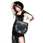 Bolso bandolera con bordado esotérico inspirado en una alforja con detalle trenzado y cinta bordada lateral rígido color negro vista con modelo