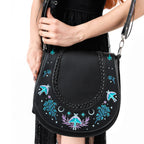 Bolso bandolera con bordado esotérico inspirado en una alforja con detalle trenzado y cinta bordada lateral rígido color negro vista con modelo cerca