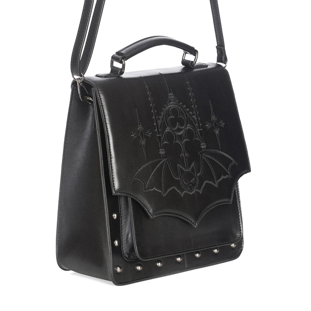 Mochila convertible a bolso bandolera o bolso de mano con bordado y solapa en forma de murciélago y remaches metálicos en la parte frontal vista ángulo con correa