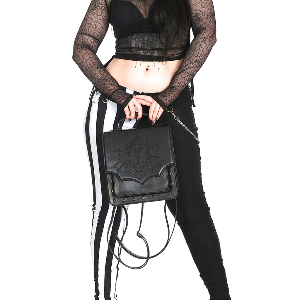 Mochila convertible a bolso bandolera o bolso de mano con bordado y solapa en forma de murciélago y remaches metálicos en la parte frontal vista modelo