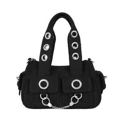 Bolso de mano o bandolera con ojales metálicos en los bolsillos y en las asas. Fabricado en tela de algodón y con esposas de decoración en la parte frontal. Vista frontal