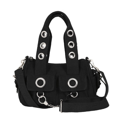 Bolso de mano o bandolera con ojales metálicos en los bolsillos y en las asas. Fabricado en tela de algodón y con esposas de decoración en la parte frontal. Vista con correa