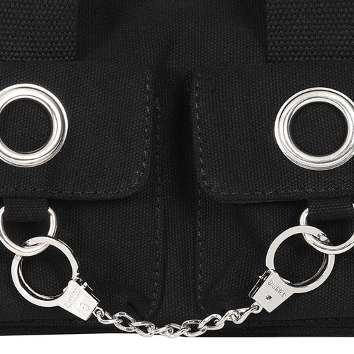 Bolso de mano o bandolera con ojales metálicos en los bolsillos y en las asas. Fabricado en tela de algodón y con esposas de decoración en la parte frontal. Vista detalles metálicos