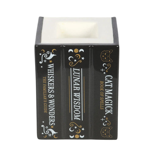 Quemador de aceites esenciales y cera con forma de tres libros de estética witchy con gato en la portada vista lomo libros sobre fondo blanco.