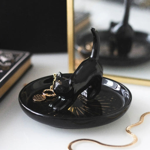 Plato para joyería con gato central con cola hacia arriba para dejar los anillos y joyas visto desde un lateral sobre un escritorio con joyas al rededor.