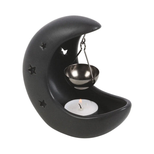 Quemador de aceite en forma de luna creciente con estrellas cut out en color negro con colgante metálico negro para poner aceite vista ángulo sobre fondo blanco con vela dentro. 