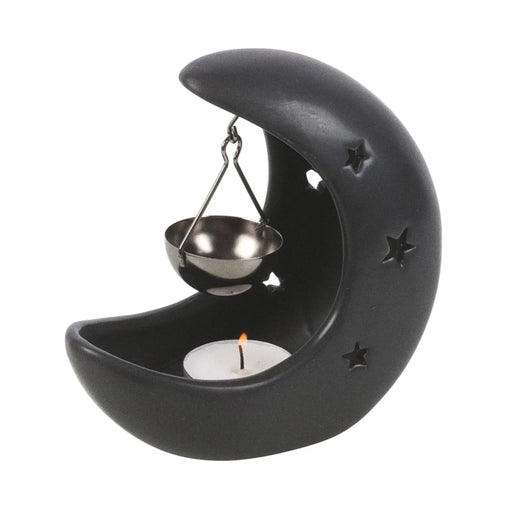 Quemador de aceite en forma de luna creciente con estrellas cut out en color negro con colgante metálico negro para poner aceite vista ángulo sobre fondo blanco con vela dentro. 