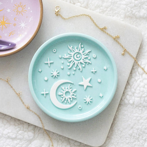 Bandeja para joyería en tono azul pastel con relieve de sol, luna y estrellas en color blanco estética whimsical y aesthetic vista desde arriba sobre escritorio con decoración al rededor.