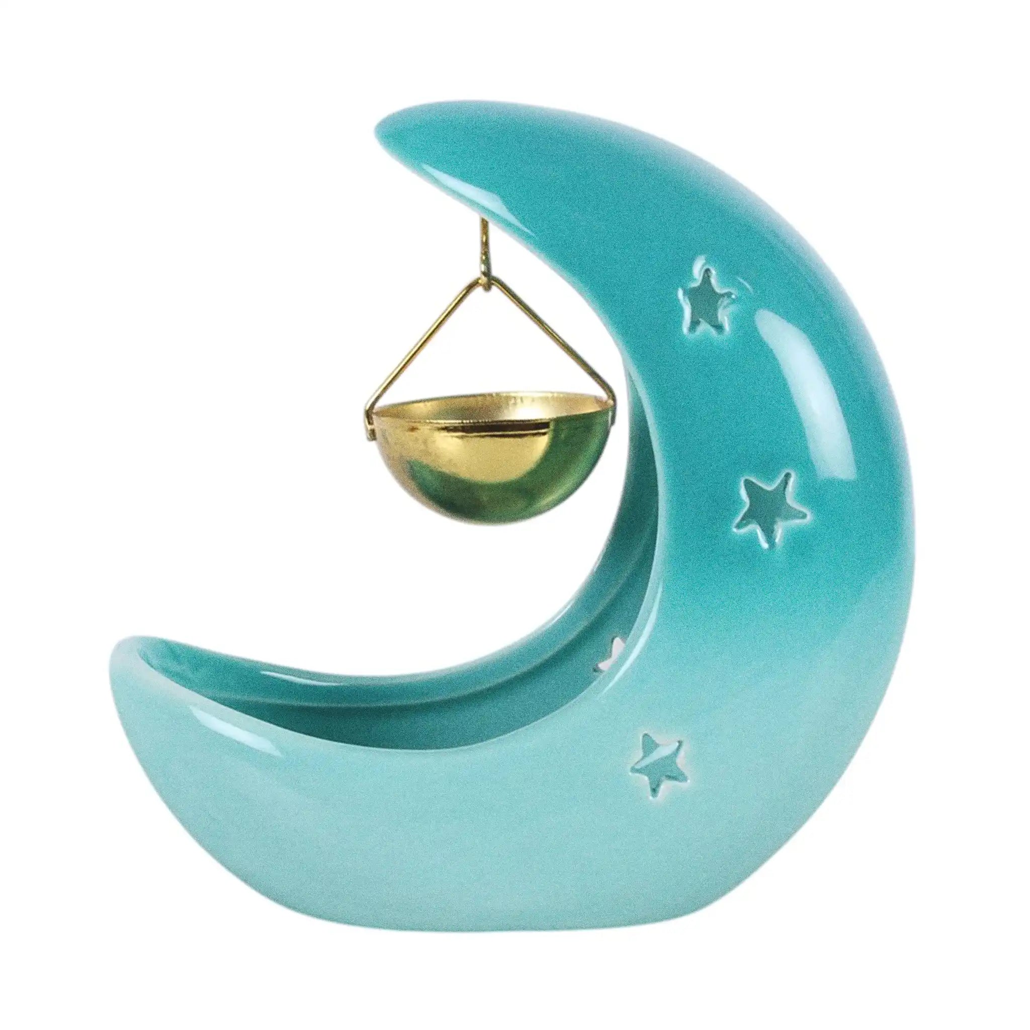 Quemador de aceites esenciales en forma de luna creciente con estrellas cut out en tono azul pastel con recipiente colgante vista posterior sobre fondo blanco.