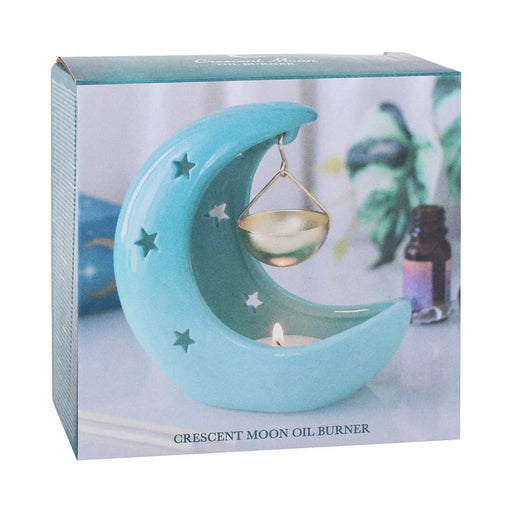 Quemador de aceites esenciales en forma de luna creciente con estrellas cut out en tono azul pastel con recipiente colgante vista packaging sobre fondo blanco.
