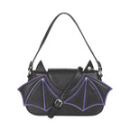 Bolso gótico negro y morado configurado como bandolera, con la correa larga y ajustable cruzada sobre el frente.