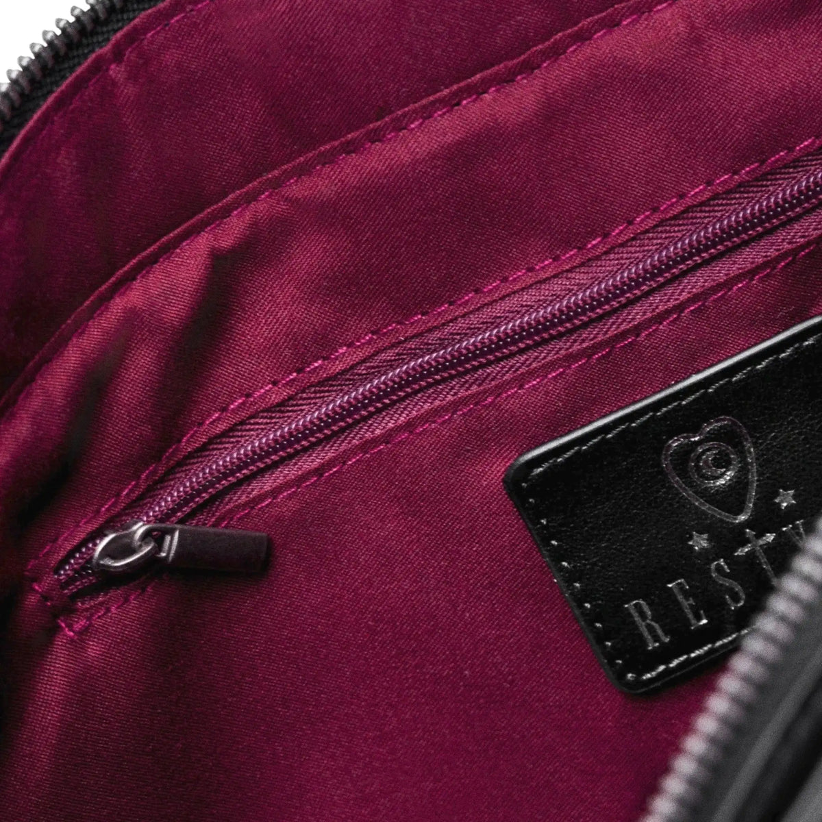 Bolso bandolera negro con diseño rígido en forma de escudo inspirado en las catedrales y la arquitectura medieval con detalles en terciopelo burdeos modelo Claretia de Restyle vista bolsillo interior con cremallera