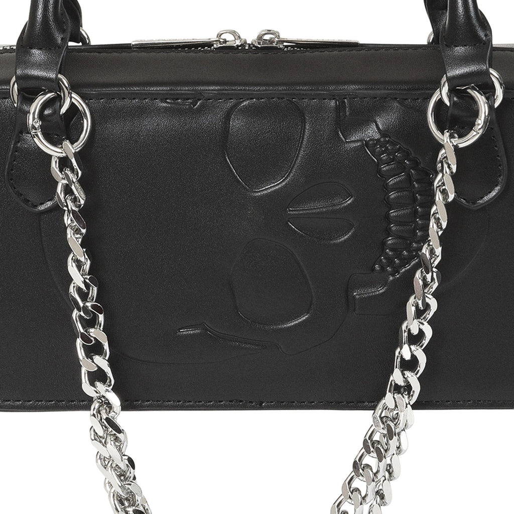 Primer plano de la calavera grabada en relieve sobre la superficie del bolso gótico negro.