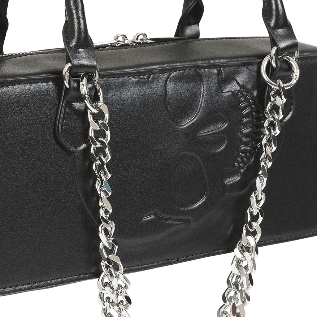 Detalle del diseño de calavera en relieve y la cadena plateada del bolso negro.