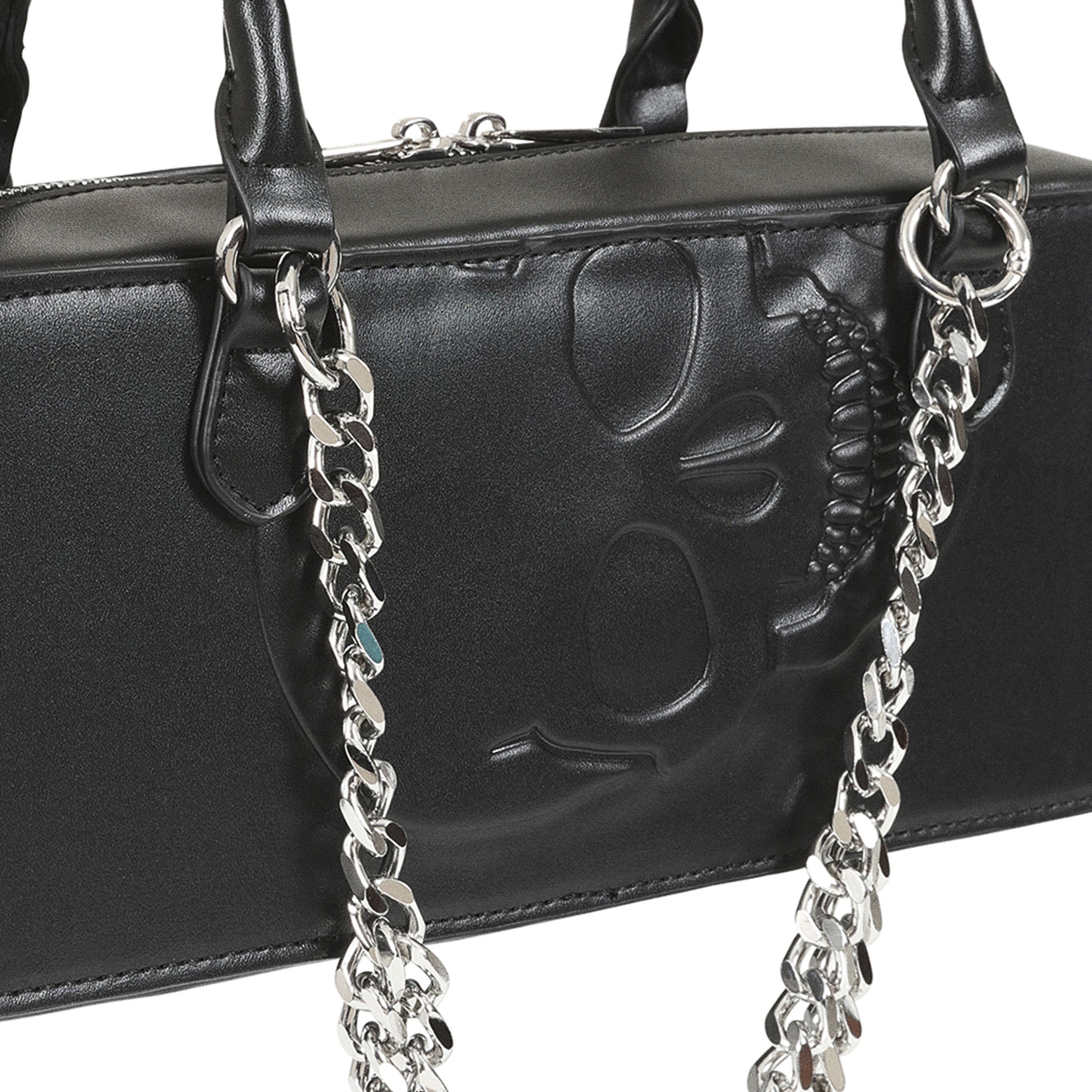 Detalle del diseño de calavera en relieve y la cadena plateada del bolso negro.