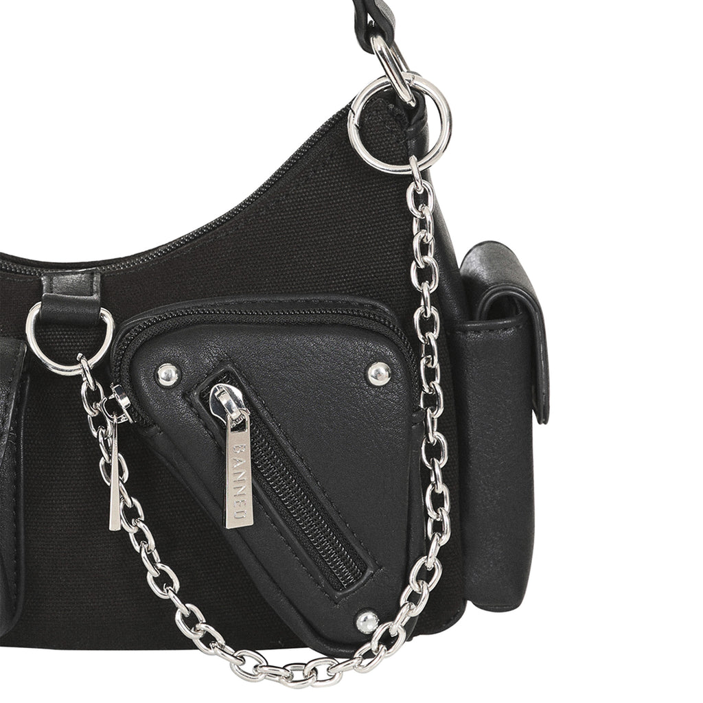 Primer plano del bolsillo con cremallera y remaches del bolso, con la cadena metálica colgando de una anilla.