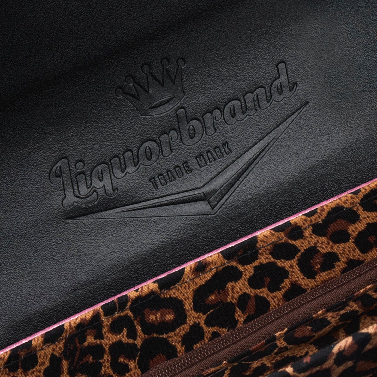 Primer plano del logo de Liquorbrand y el forro de leopardo en el interior de la solapa del bolso.
