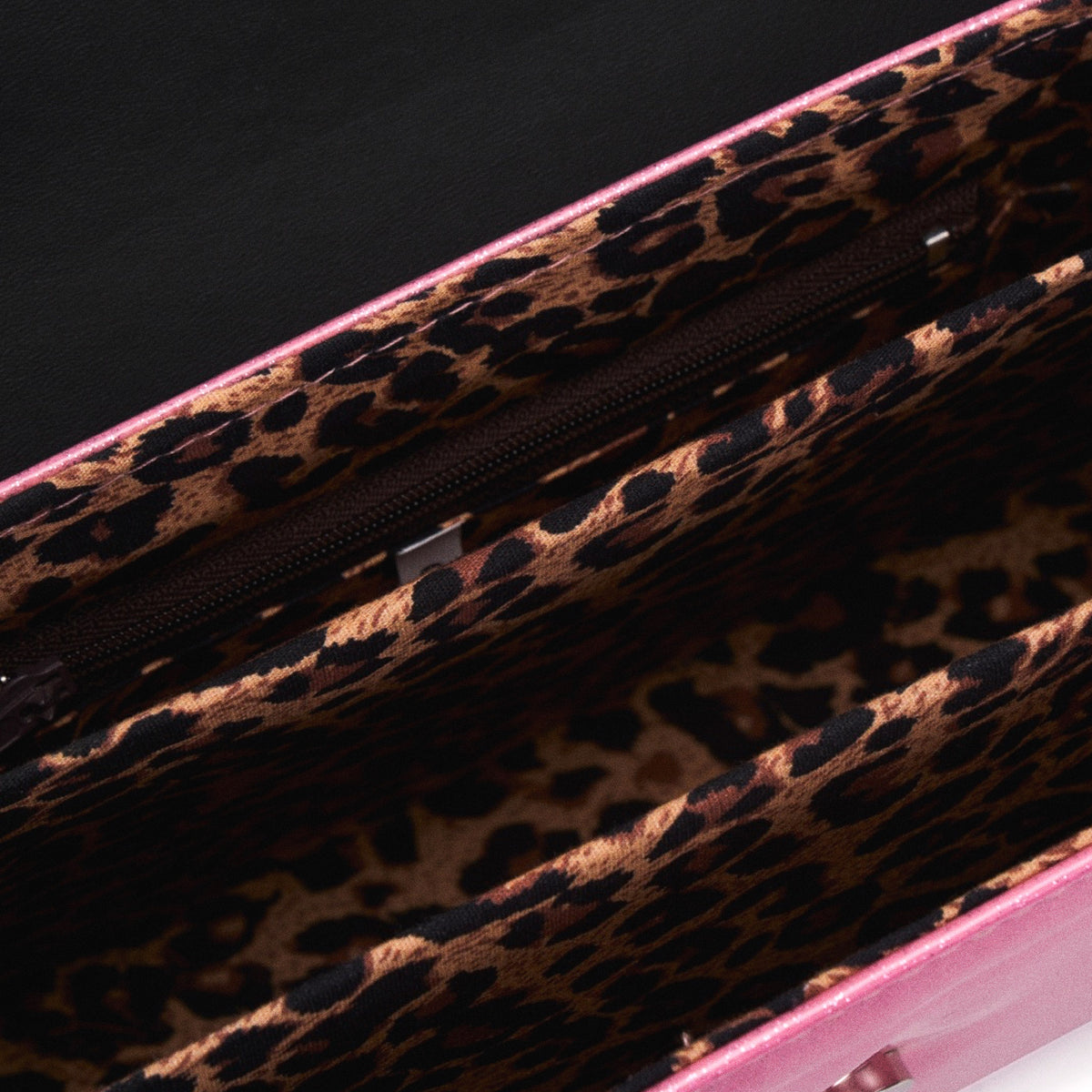Interior del bolso The Rumbler con forro de estampado de leopardo y un compartimento central con cremallera.