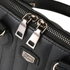 Detalle de la cremallera metálica con doble tirador sobre la parte superior del bolso negro.