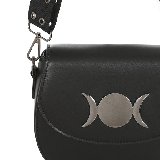 Primer plano del adorno metálico de la Triple Luna en la solapa del bolso gótico.