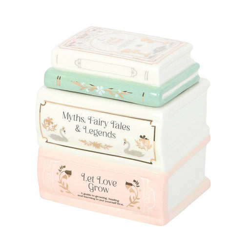 Quemador de aceites esenciales y cera en forma de libros apilados estilo fairy aesthetic vista de ángulo sobre fondo blanco.