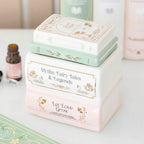 Quemador de aceites esenciales y cera en forma de libros apilados estilo fairy aesthetic vista ángulo sobre escritorio con decoración al rededor.