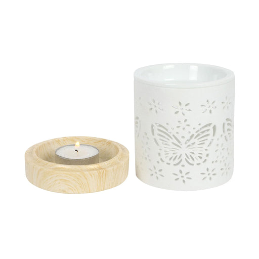 Quemador de aceites esenciales y calentador de cera con diseño de mariposa calada en blanco y base de madera vista frontal con parte de abajo quitada sobre fondo blanco.