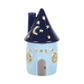 Quemador de aceites esenciales con decoración estilo whimsical y celestial de estrellas y lunas en pequeña cabaña acogedora vista frontal sobre fondo blanco.