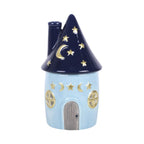 Quemador de aceites esenciales con decoración estilo whimsical y celestial de estrellas y lunas en pequeña cabaña acogedora vista frontal sobre fondo blanco.