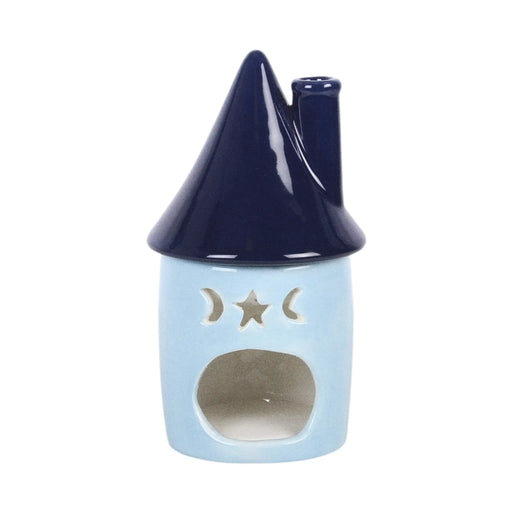 Quemador de aceites esenciales con decoración estilo whimsical y celestial de estrellas y lunas en pequeña cabaña acogedora vista parte posterior abertura para vela sobre fondo blanco.