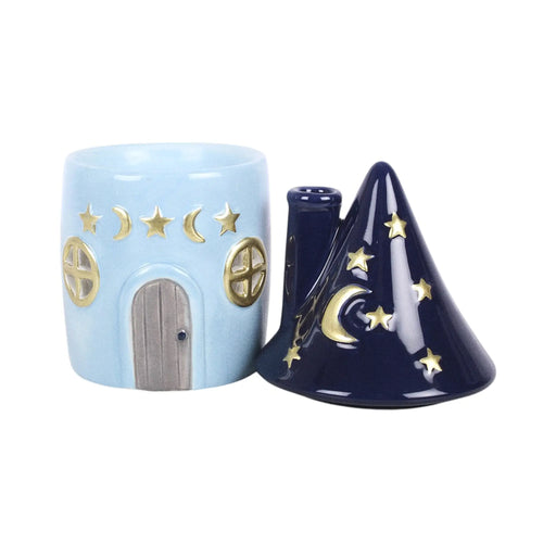 Quemador de aceites esenciales con decoración estilo whimsical y celestial de estrellas y lunas en pequeña cabaña acogedora vista frontal con tapa abierta sobre fondo blanco.