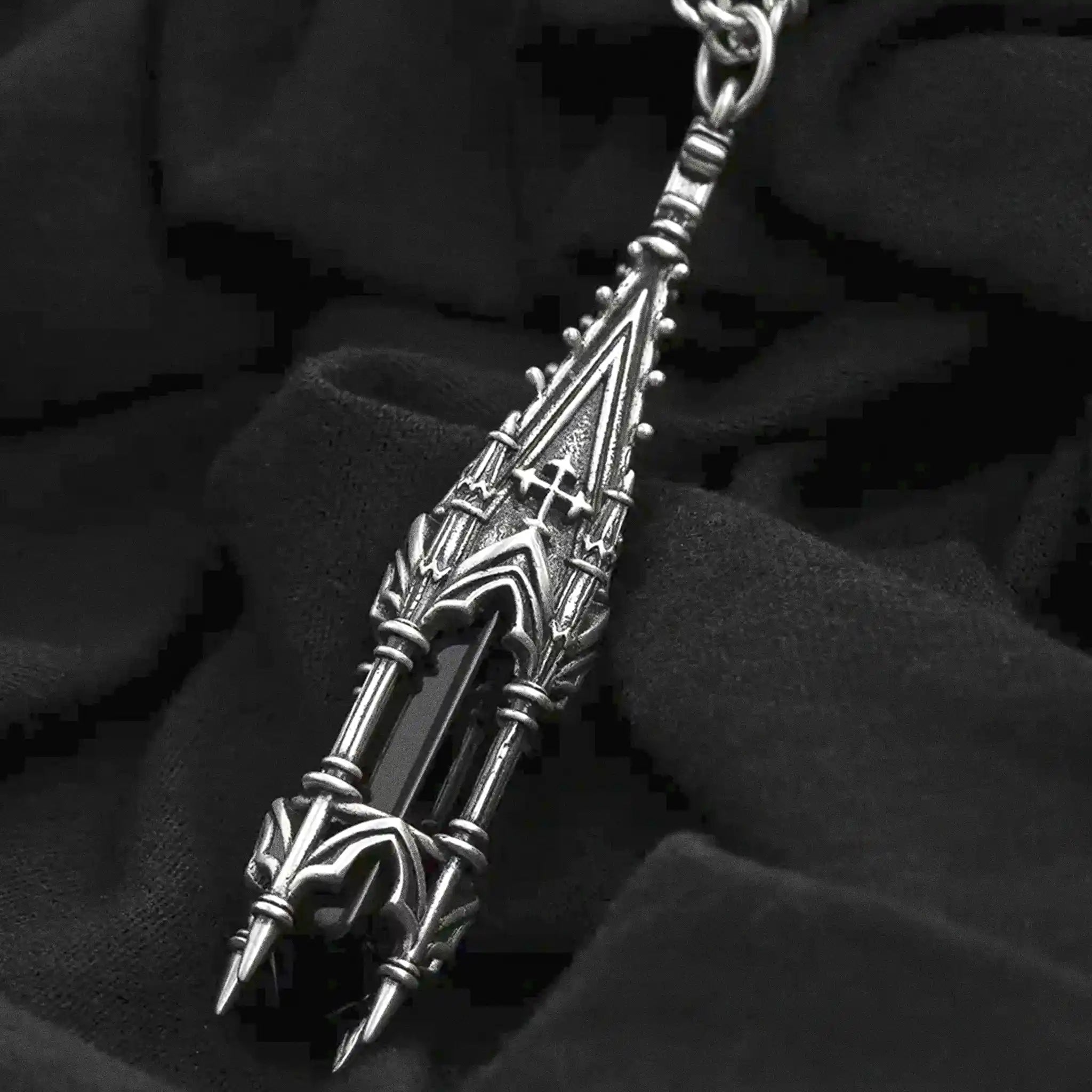 Collar con colgante inspirado en una torre de una iglesia gótica con cruces y ventanales y una piedra negra de vidrio fabricado en latón y bañado en plata de ley vista detalle del colgante sobre fondo negro