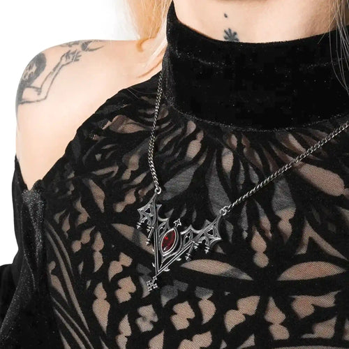 Collar con silueta de murciélago creada por detalles inspirados en catedrales góticas y piedra roja central engarzada fabricado en latón y plata de ley de Restyle vista en el cuello de una modelo
