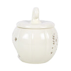 Quemador de aceites esenciales y calentador de cera con diseño de calabaza calado con motivos otoñales en blanco roto vista lateral sobre fondo blanco.