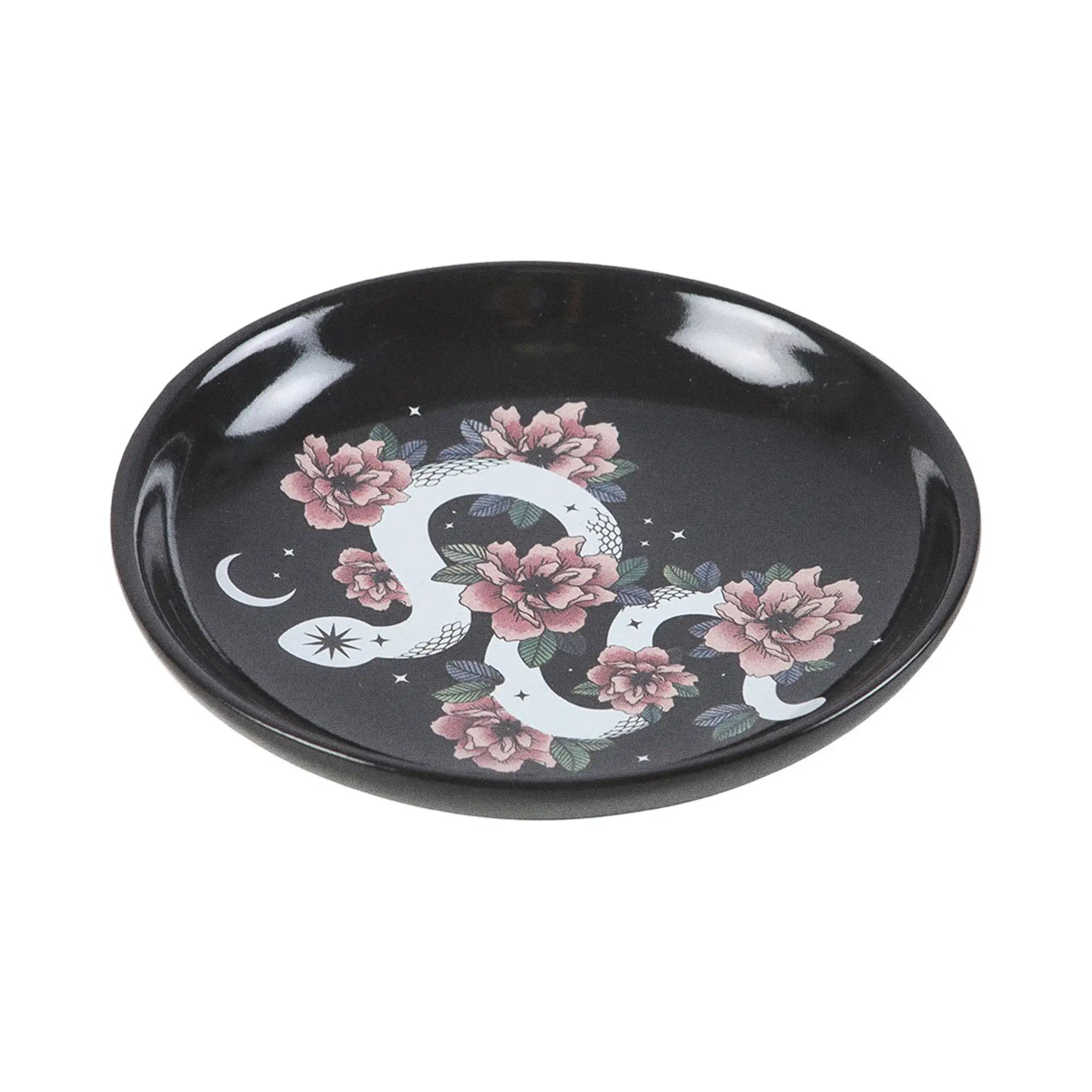 Plato de joyería redondo negro con diseño de serpiente enroscada en flores, estrellas y luna vista desde un lateral con fondo blanco.