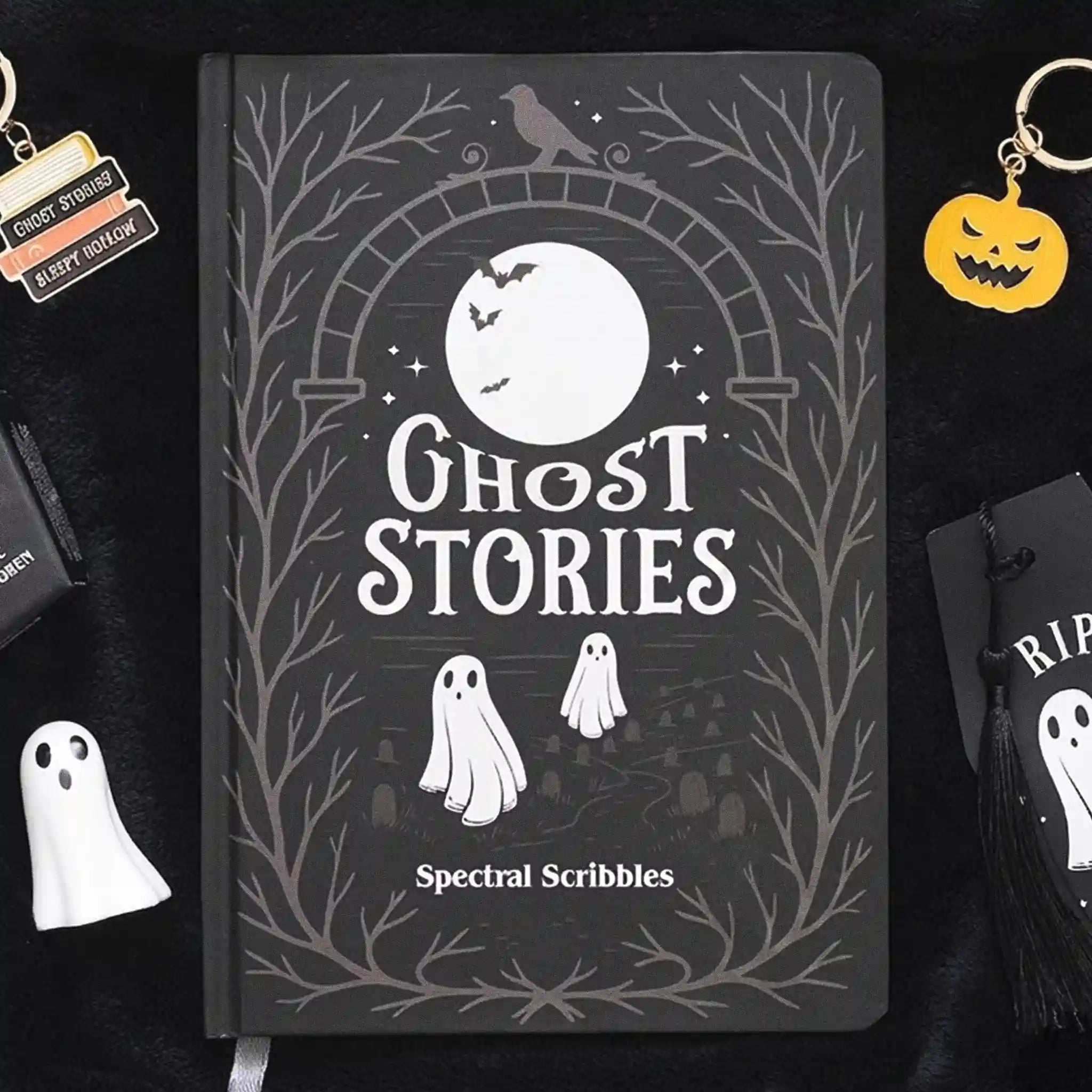 Portada de libreta A5 de fantasmas estilo spooky apoyada sobre una tela negra con decoración al rededor.