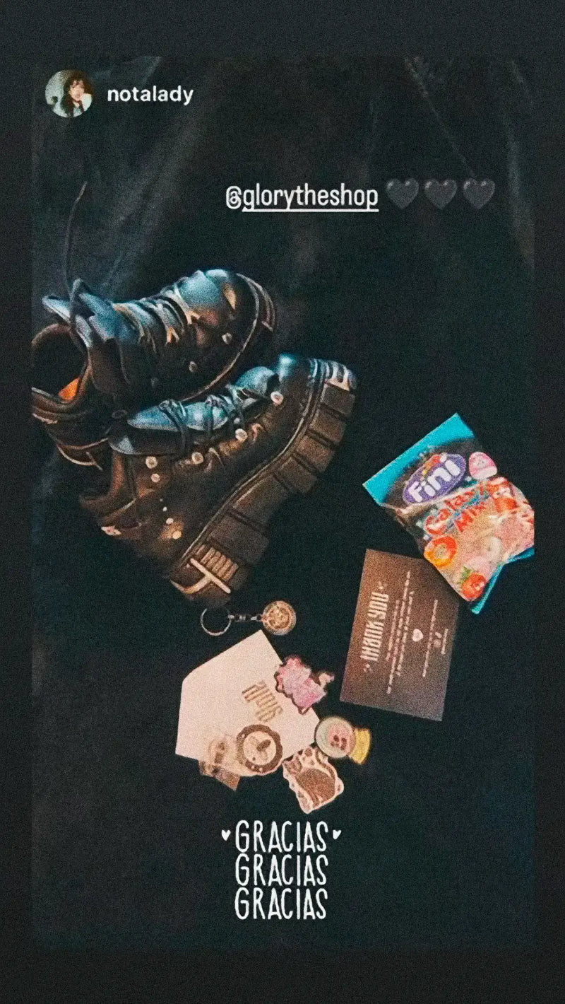 Pair of black gothic platform boots with metal hardware, displayed on a dark background with sweets, stickers, and a thank you card.