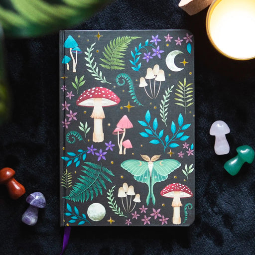 Libreta forestcore sobre fondo de tela con decoración al rededor.