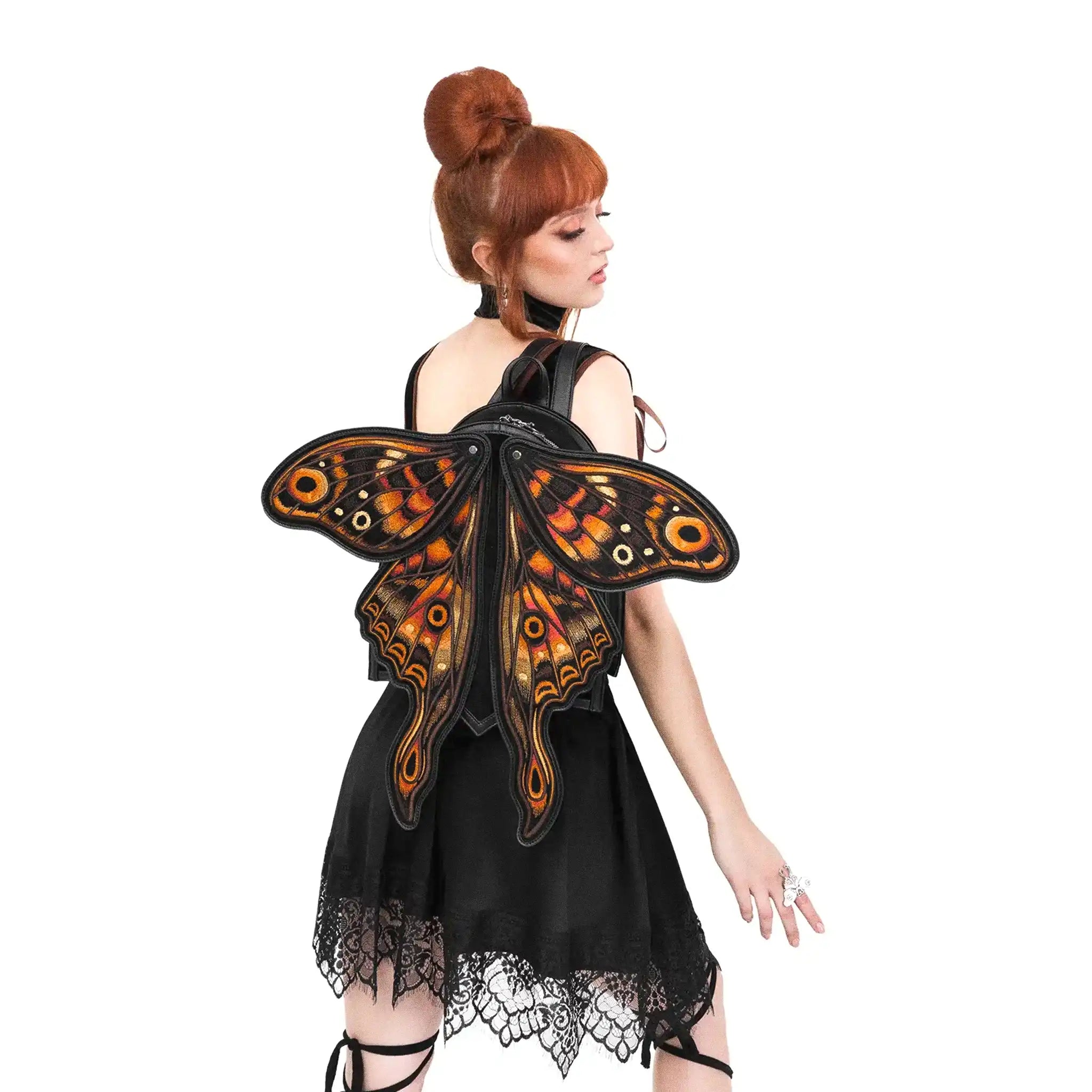 Mochila con forma de polilla y alas móviles con impresionante bordado en tonos fuego fabricada en tejido vegano vista con alas abiertas en hombro de modelo