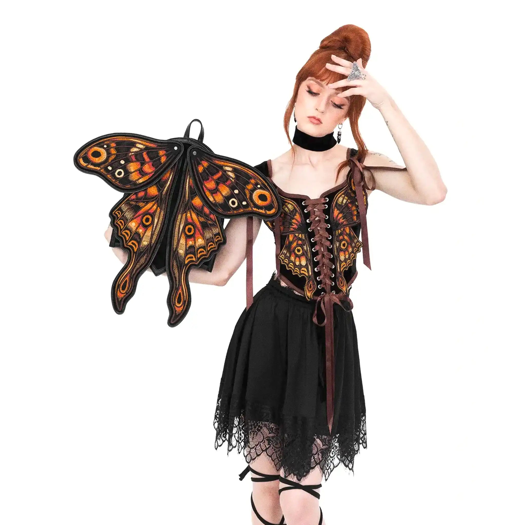 Mochila con forma de polilla y alas móviles con impresionante bordado en tonos fuego fabricada en tejido vegano vista con alas abiertas en la mano de la modelo