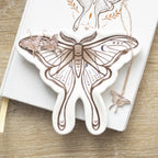 Bandeja para joyería con forma de polilla en blanco con estampado en tonos marrones sobre escritorio con joyería al rededor.