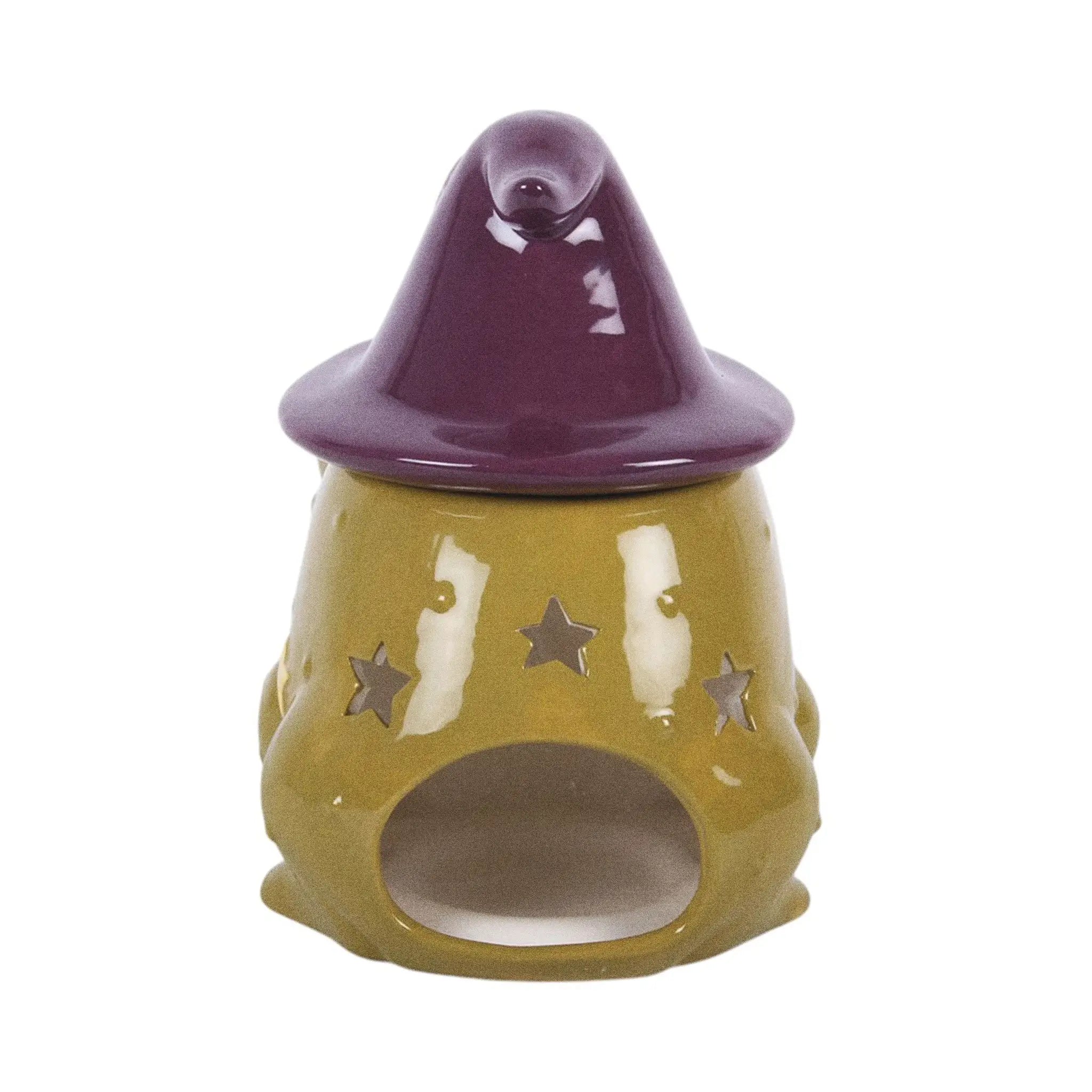 Quemador de aceites esenciales y calentador de cera en forma de sapo mágico con gorro de brujo con estrellas y luna estilo whimsical vista posterior de espacio para vela sobre fondo blanco.