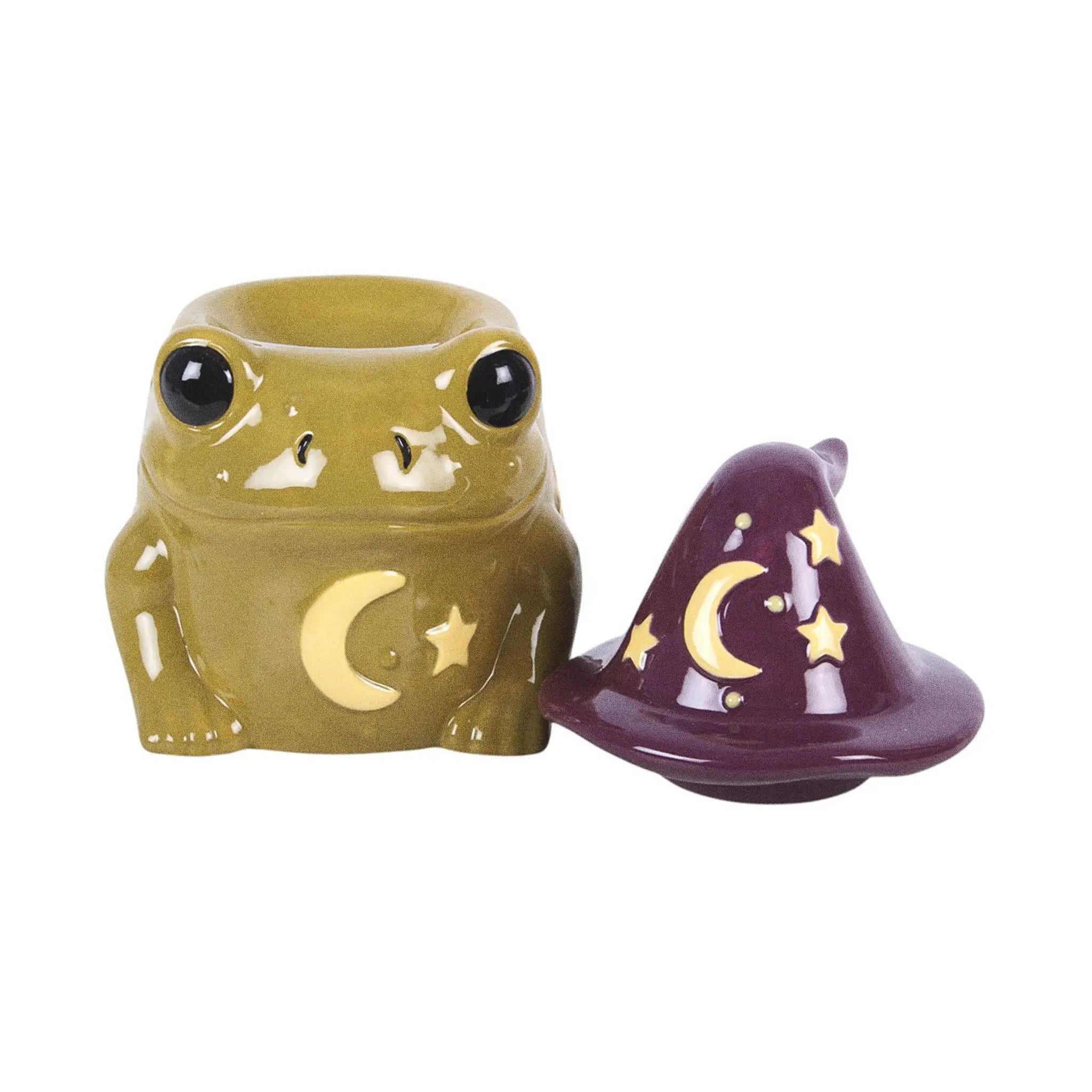 Quemador de aceites esenciales y calentador de cera en forma de sapo mágico con gorro de brujo con estrellas y luna estilo whimsical vista frontal con sombrero quitado sobre fondo blanco.