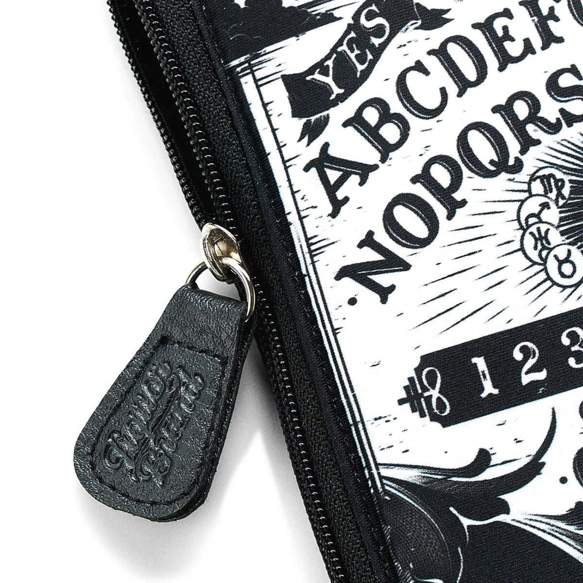 Primer plano del tirador de cremallera de cuero sintético grabado con el logo de Liquorbrand del neceser Ouija.