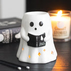 Quemador de aceites esenciales en forma de fantasma leyendo un libro estilo spooky halloween vista frontal sobre escritorio con decoración al rededor.