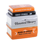Quemador de aceite y calentador de ceras aromáticas en forma de libros apilados de estética de Halloween y Spooky en naranja, negro y gris vista ángulo sobre fondo blanco.